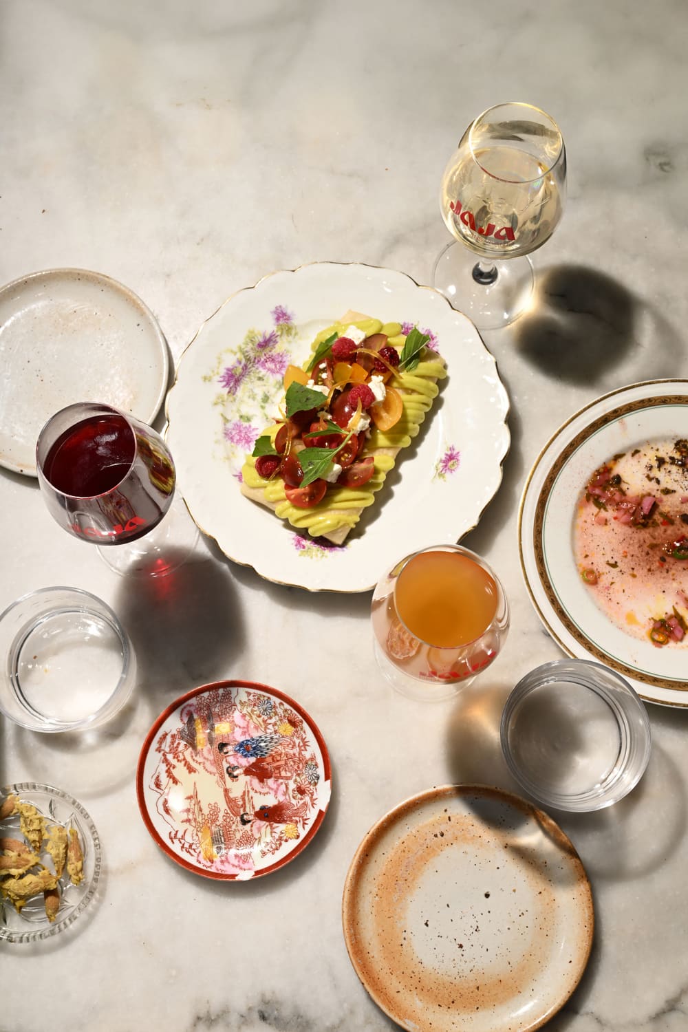 Table dressée — assiette colorée, vins nature et vaisselle chinée