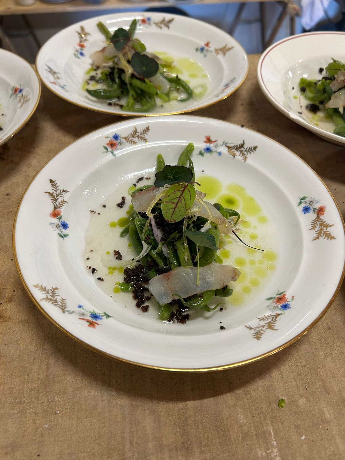 Poisson cru, haricots verts et capucine sur vaisselle ancienne fleurie
